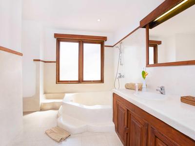 Bagno luminoso con vasca da bagno integrata, finestra in legno e lavabo piano con mobile in legno.