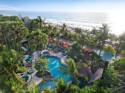 Tropische Ferienanlage mit Pool, Palmen und Blick aufs offene Meer bei Sonnenschein.