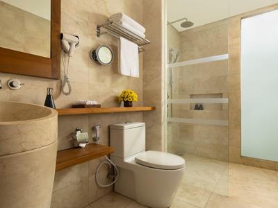 Modernes Hotelbad mit beige Fliesen, Dusche mit Glasabtrennung und eleganten Armaturen.