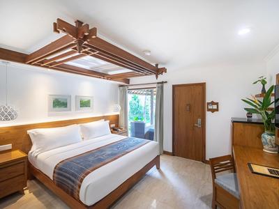Helles Hotelzimmer mit Doppelbett, Holzmöbeln und Zugang zu einem Balkon oder Garten.