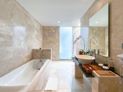 Helles Badezimmer mit Badewanne, Waschbecken auf Holztisch und großer Spiegelwand.