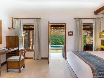 Hell eingerichtetes Hotelzimmer mit Bett, Schreibtisch und Blick auf den Garten.