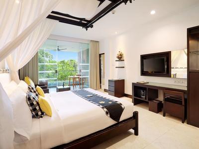 Helles Schlafzimmer mit großem Bett, Balkon, Fernseher und modernen Holzmöbeln.