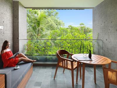 Balkon met moderne zitmeubelen en uitzicht op groene tuin in hotelachtige omgeving.