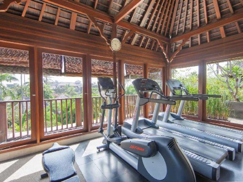 Fitnessruimte met loopbanden in een open paviljoen met houten dak en uitzicht op groen