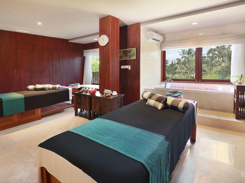 Tweepersoonskamer met twee eenpersoonsbedden, tapijten en groot raam met uitzicht op groen.