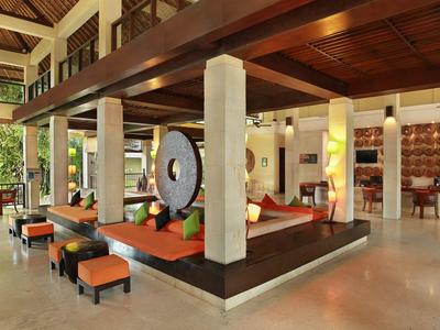 Amplia área abierta de vestíbulo de hotel con asientos, techo con vigas de madera y luz natural.