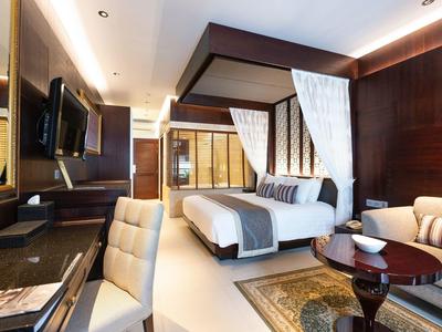 Modernes Hotelzimmer mit Himmelbett, Schreibtisch, Fernseher und elegantem Holzmobiliar.