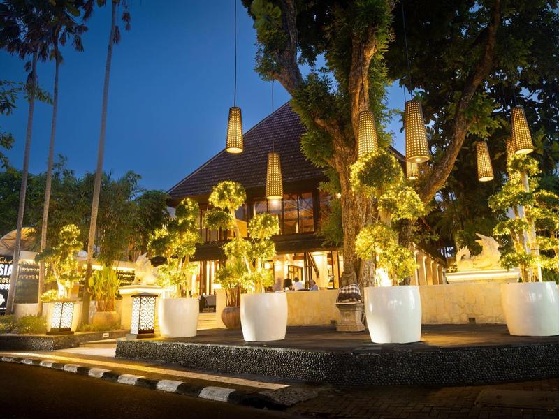 Verlichte hotelomgeving met tropische planten en een rustige avondstemming.