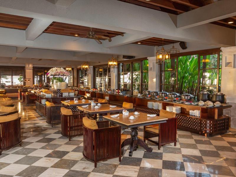 Ruim restaurant met geruite vloer, houten tafels en leren stoelen in warme sfeer.