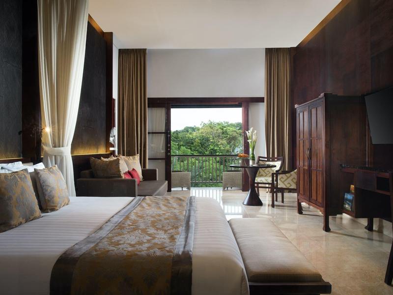 Modern hotelkamer met groot bed, balkon en uitzicht op groen landschap.