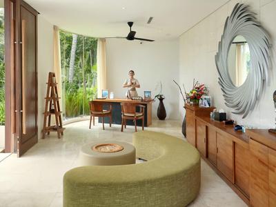 Heller, moderner Wohnraum mit grünem geschwungenem Sofa, Holzkommode und großem Spiegel.