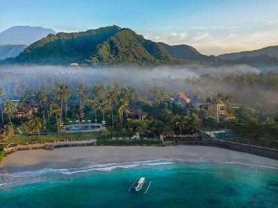 Spiaggia con acqua turchese chiara, barca e colline boscose sullo sfondo.