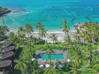 Spiaggia tropicale con palme, acqua turchese limpida e una piscina in un resort vacanze.