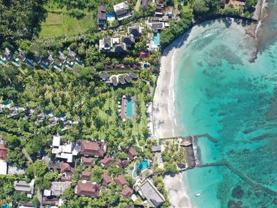 Veduta aerea di un hotel tropicale con piscina accanto a una spiaggia di sabbia bianca e acqua turchese.