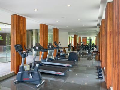 Palestra moderna con tapis roulant, biciclette e pilastri in legno in un hotel.