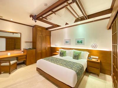 Helles Schlafzimmer mit Holzmöbeln, Doppelbett, Spiegel, Tisch und dekorativen Kissen.