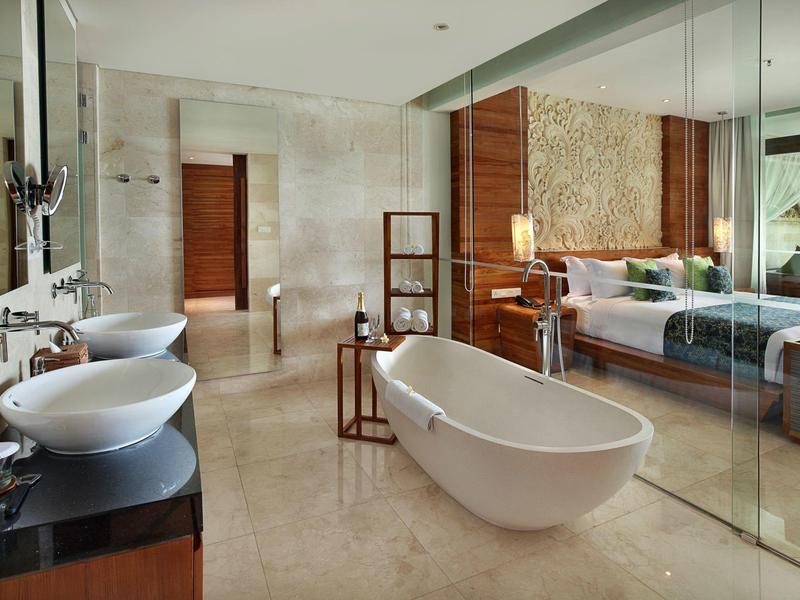 Modernes, geräumiges Badezimmer mit freistehender Badewanne, Doppelwaschbecken und Glaswand zum Schlafzimmer.