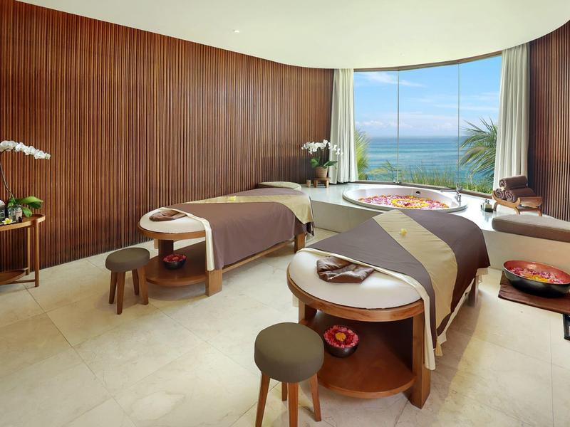 Modernes Spa-Zimmer mit zwei Massageliegen, Holzwänden, großem Fenster und Meerblick.