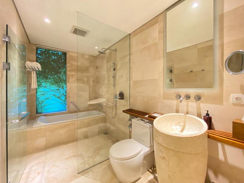 Modernes Badezimmer mit Glasduschwand, Badewanne, rundem Waschbecken und großem Fenster.