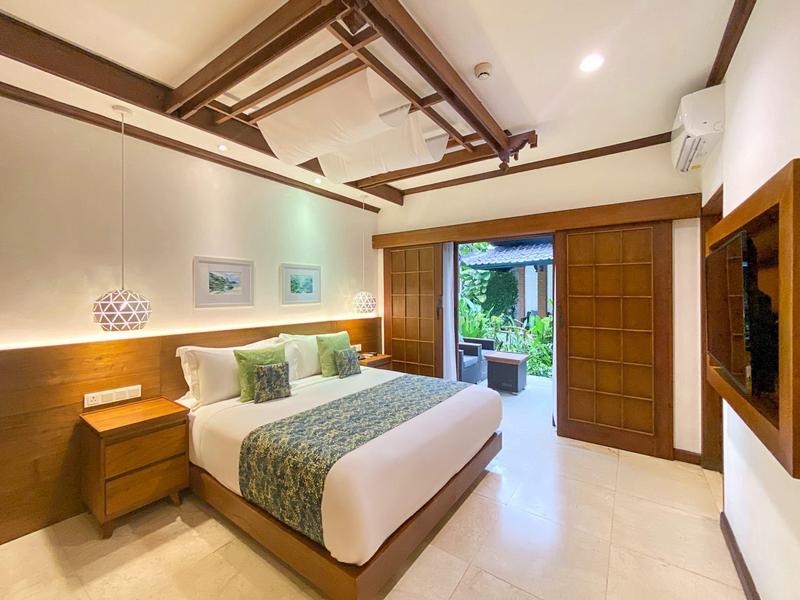 Helles Schlafzimmer mit Doppelbett, Holzdecke und Tür zu Terrasse mit Gartenblick.