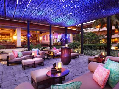 Gezellige buitenlounge met banken en kussens in hotelomgeving bij nacht met sfeerverlichting.