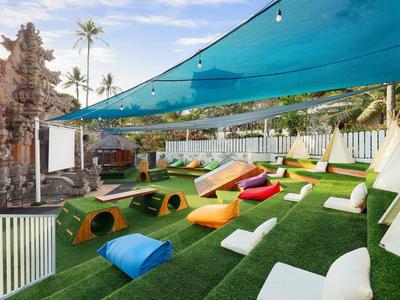 Gezellig buitengebied met kleurrijke kussens en zonnescherm over groen kunstgras.