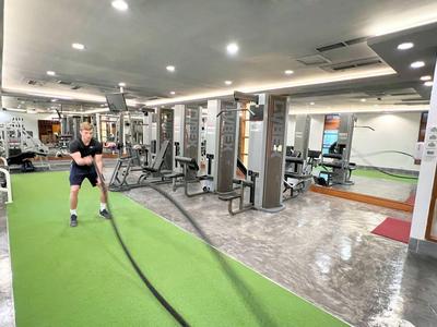 Person training with battle ropes in a modern gym with green flooring.
