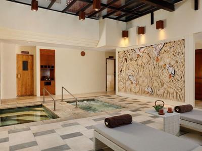 Moderne wellnessruimte met bubbelbad, ligstoelen en stijlvolle wanddecoratie.