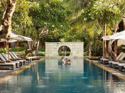 Relaxing pool area with loungers and lush greenery at a resort.