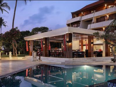 Luxe hotel met verlicht zwembad en palmbomen in het schemerlicht.