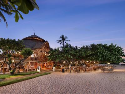 Evening beach bar with palm trees, sand, and seating by the sea