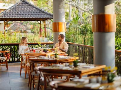 Koppel zit op open veranda en geniet van een maaltijd met natuurzicht.