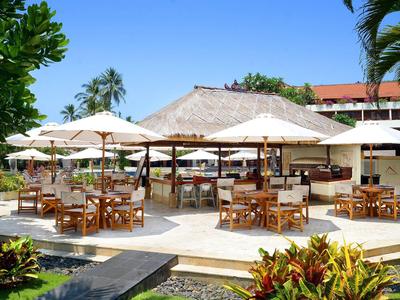 Openluchtrestaurant met houten tafels en witte parasols in een tropische tuin