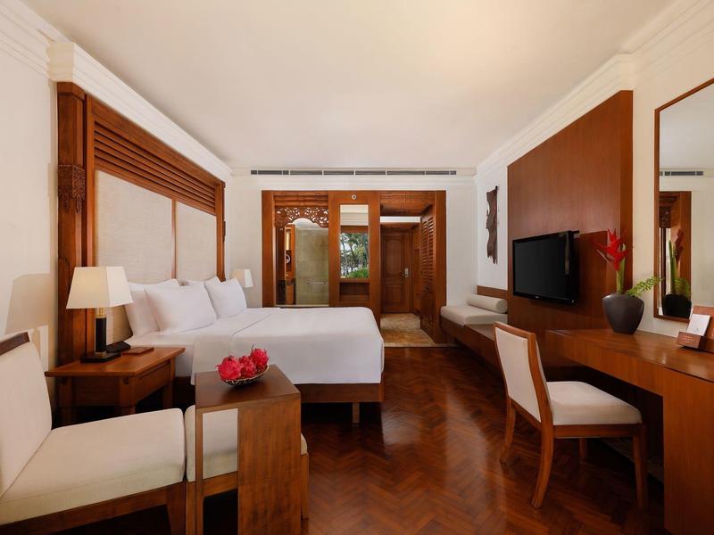 Elegant hotelkamer met tweepersoonsbed, houten meubels en bureau met tv.