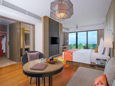 Modernes Hotelzimmer mit großem Bett, Balkon und gemütlicher Sitzecke.