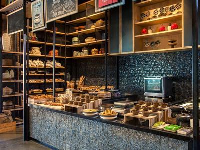 Gemütliches Café mit Holzregalen, Theke und Auswahl an Kaffee und Gebäck.