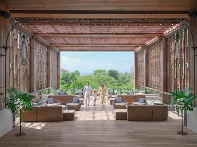 Offener Lounge-Bereich mit Sofas, Pflanzen und Blick auf Garten und Meer.