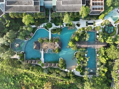 Luftaufnahme eines großen Pools mit Insel, Brücken und viel Grün rundum.