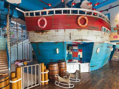 Kinderspielbereich mit einem großen Schiff als Spielhaus in einem Ferienresort.