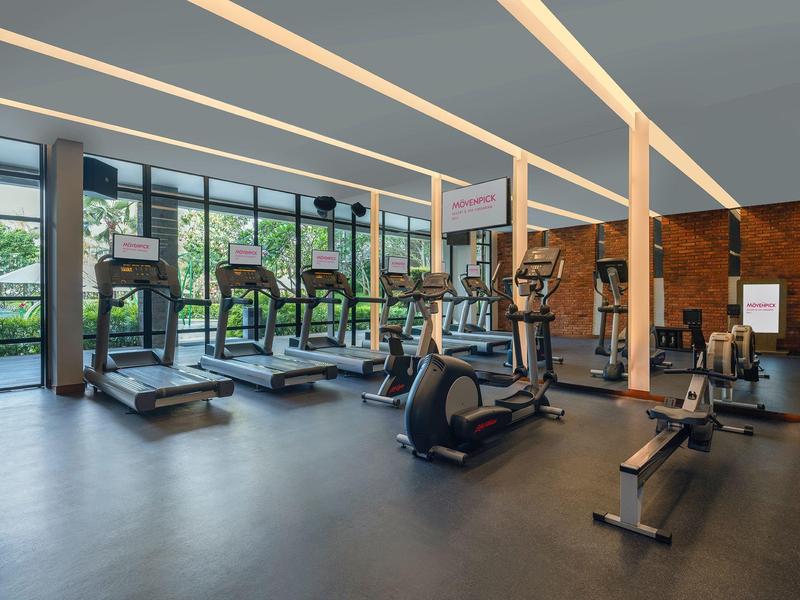 Moderner Fitnessraum mit Laufbändern, Fahrrädern und Gewichten in hellem Raum.