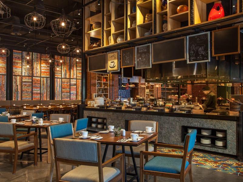 Modernes Restaurant mit Holzmöbeln und dekorativer Beleuchtung in einem Hotel.