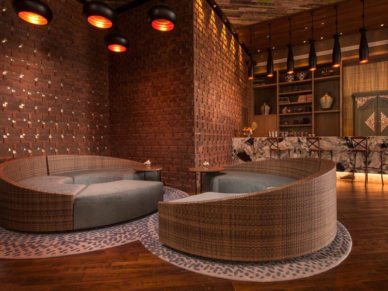 Gemütliche Rundsofas in warm beleuchtetem Hotel-Lounge-Bereich mit Holzboden.