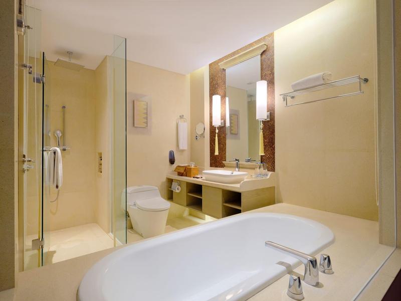 Helles Badezimmer mit Badewanne, Dusche, Toilette und Waschbecken mit Spiegel.