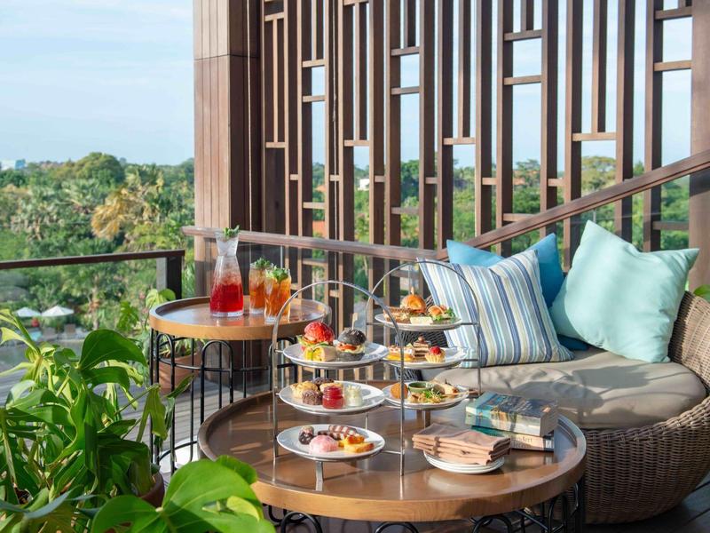 Gemütliche Balkonlounge mit Cocktails und Snacks, umgeben von Pflanzen und Blick ins Grüne.