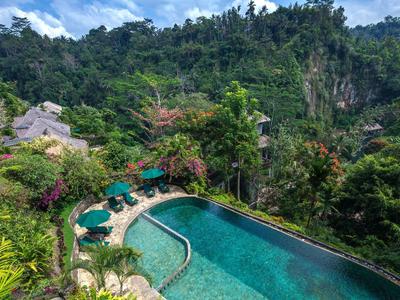 Swimming pool surrounded by lush tropical vegetation and hills in the background.
