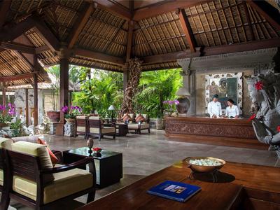 Open-air hotel lobby with wooden ceiling, comfortable seating, and lush garden views.