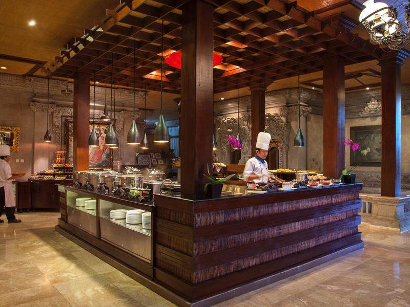 Elegant hotel buffet with dark wood counters and a chef serving food.