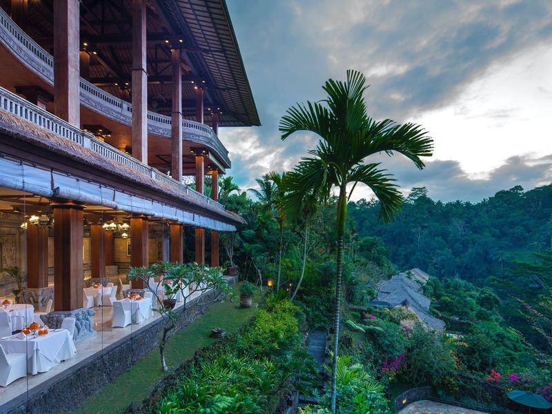 Outdoor dining area next to a tropical garden and forest view at dusk