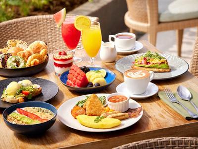 Stół śniadaniowy z różnymi kolorowymi potrawami i napojami.